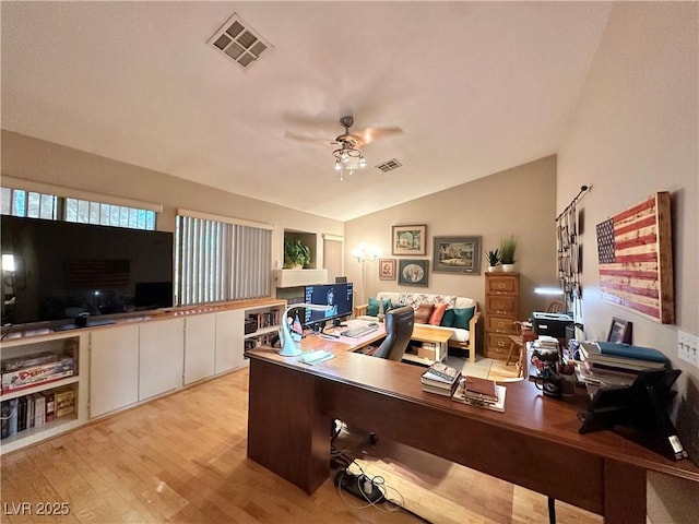 office featuring light wood-style floors, a ceiling fan, vaulted ceiling, and visible vents