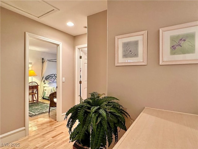 hall featuring recessed lighting, baseboards, light wood-style flooring, and attic access