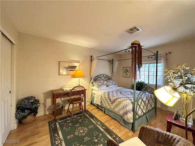 bedroom with visible vents, light wood-style floors, and a closet