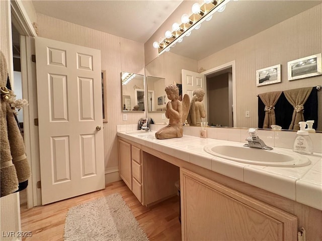 bathroom with a sink, double vanity, and wood finished floors