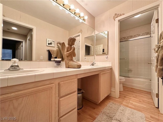bathroom featuring double vanity, toilet, a sink, and wood finished floors