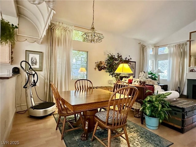 dining room featuring light wood-style floors, an inviting chandelier, and lofted ceiling