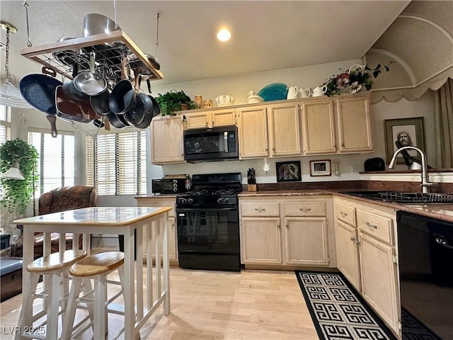 kitchen featuring light wood-type flooring, a sink, black appliances, and light brown cabinets