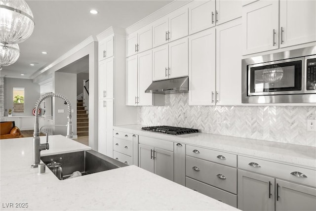 kitchen with tasteful backsplash, stainless steel appliances, under cabinet range hood, and a sink