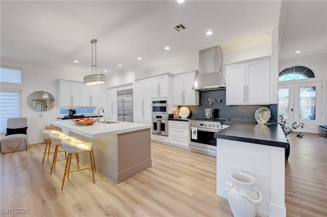 3091 Via Del Corso, Henderson, NV 89052 - kitchen featuring wall chimney range hood, a breakfast bar, a sink, french doors, and stainless steel appliances