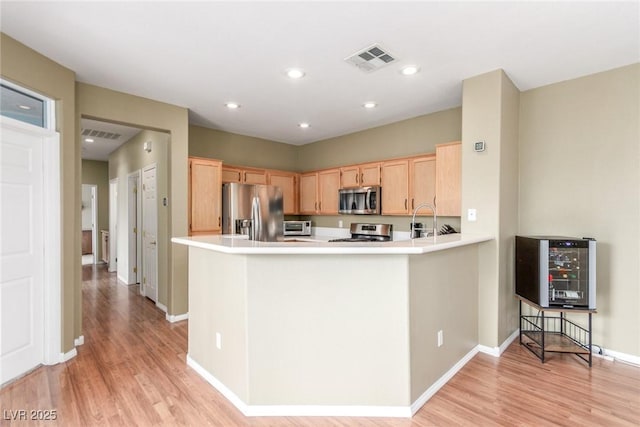 kitchen with stainless steel appliances, light brown cabinets, light wood-type flooring, baseboards, and light countertops