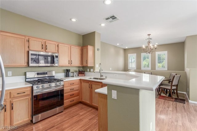kitchen with a sink, stainless steel appliances, light brown cabinetry, visible vents, and a peninsula