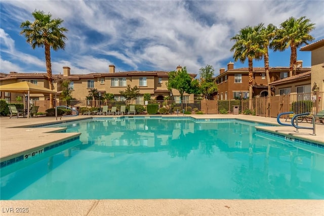 pool with a patio, fence, and a residential view