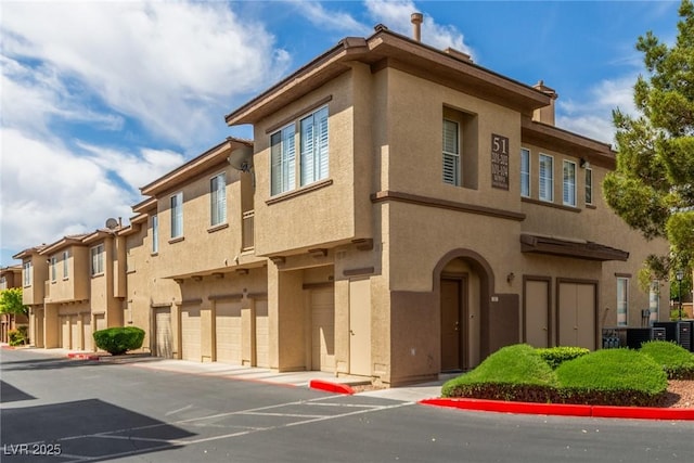 view of building exterior with a residential view, an attached garage, and central AC unit