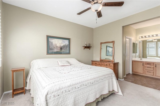 bedroom featuring baseboards, light carpet, connected bathroom, and ceiling fan