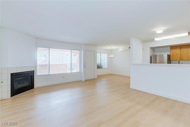 8450 Alta Dr Unit 136, Las Vegas, NV 89145 - unfurnished living room with a tiled fireplace, baseboards, and light wood finished floors