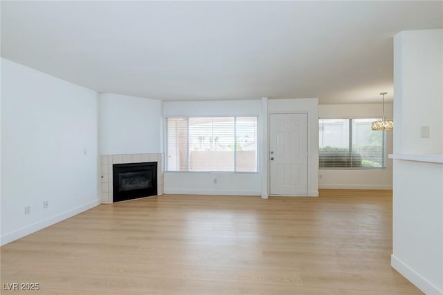 8450 Alta Dr Unit 136, Las Vegas, NV 89145 - unfurnished living room featuring baseboards, a tiled fireplace, and light wood-type flooring