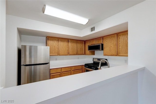 8450 Alta Dr Unit 136, Las Vegas, NV 89145 - kitchen with visible vents, stainless steel appliances, light countertops, and brown cabinetry