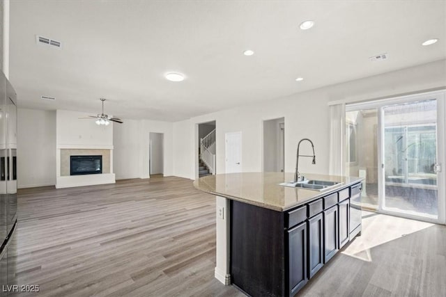 kitchen with light wood finished floors, a ceiling fan, a sink, and visible vents