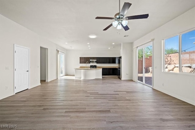 unfurnished living room with light wood finished floors, recessed lighting, ceiling fan, and baseboards