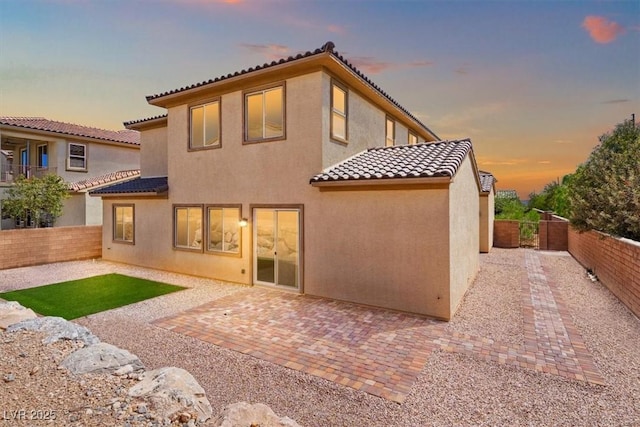 rear view of property featuring a patio, a fenced backyard, stucco siding, and a tiled roof