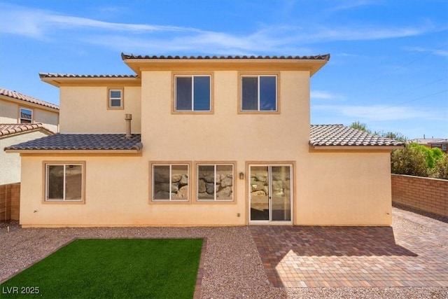 back of house featuring stucco siding, a tile roof, a patio, and a fenced backyard