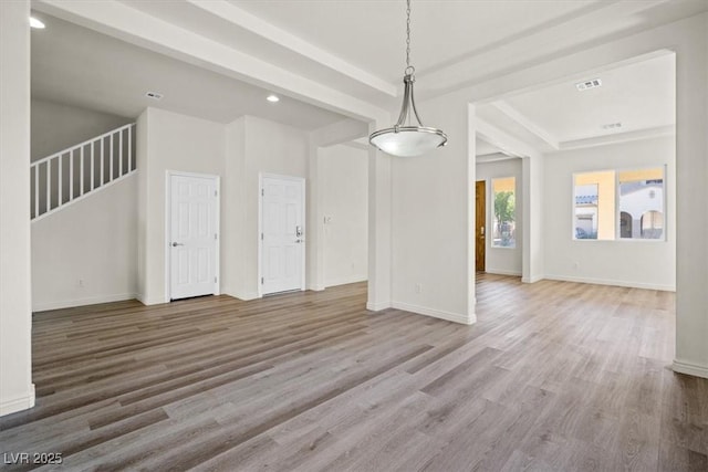 unfurnished living room with recessed lighting, wood finished floors, baseboards, visible vents, and a raised ceiling