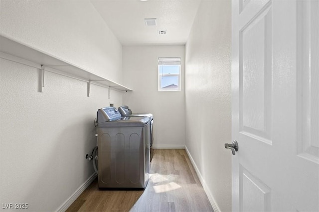 washroom featuring baseboards, wood finished floors, separate washer and dryer, and laundry area