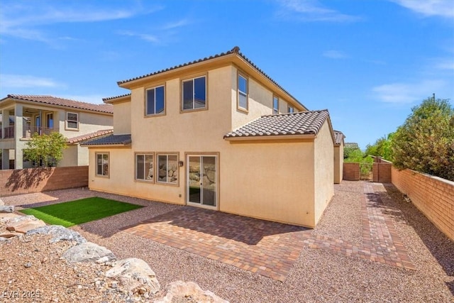 rear view of property featuring a tile roof, stucco siding, and a fenced backyard