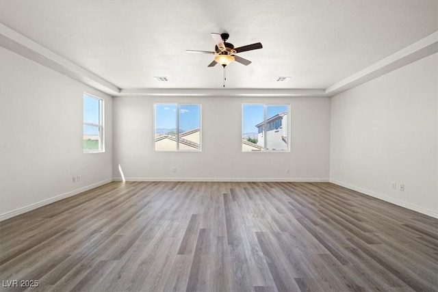 unfurnished room with baseboards, visible vents, wood finished floors, and ceiling fan