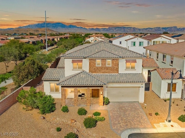 mediterranean / spanish home featuring driveway, a tile roof, stucco siding, a mountain view, and fence
