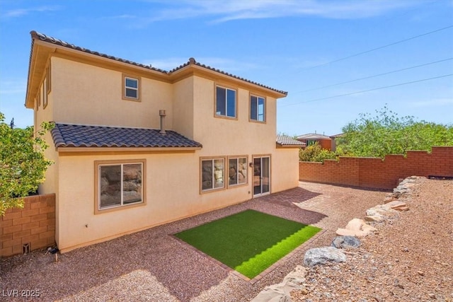 back of property with a tile roof, stucco siding, and a fenced backyard