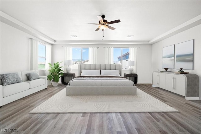 bedroom with wood finished floors, a ceiling fan, and visible vents