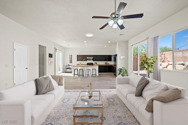 living room featuring a healthy amount of sunlight, ceiling fan, recessed lighting, and light wood-style flooring