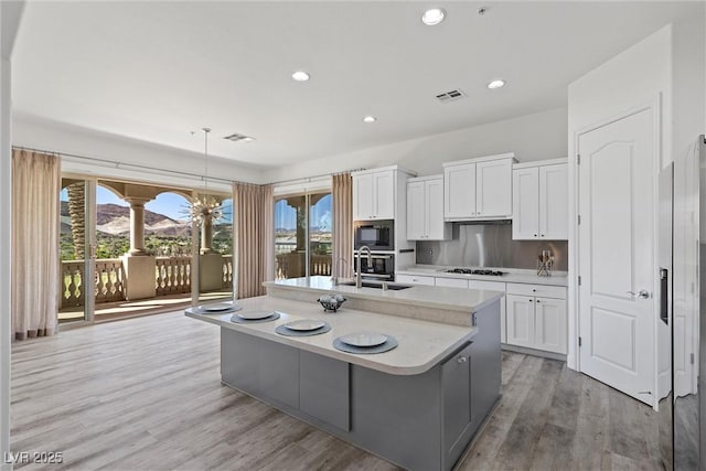 kitchen with a wealth of natural light, light countertops, gas cooktop, visible vents, and built in microwave