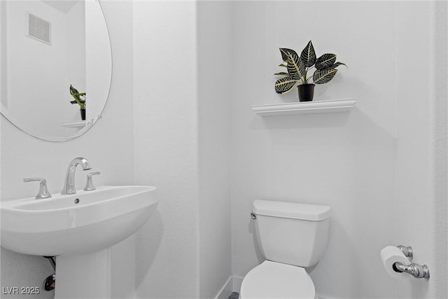 bathroom featuring baseboards, visible vents, toilet, and a sink