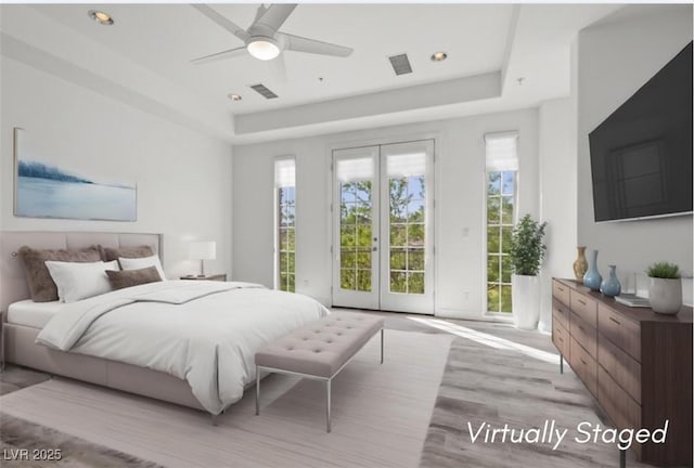 bedroom with a tray ceiling, visible vents, access to outside, and light wood-style floors