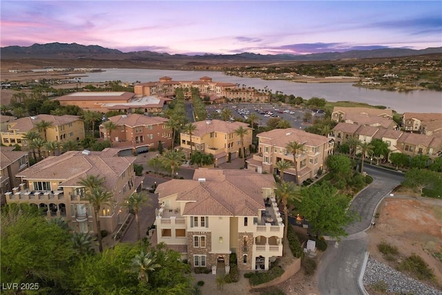 aerial view at dusk featuring a water and mountain view and a residential view