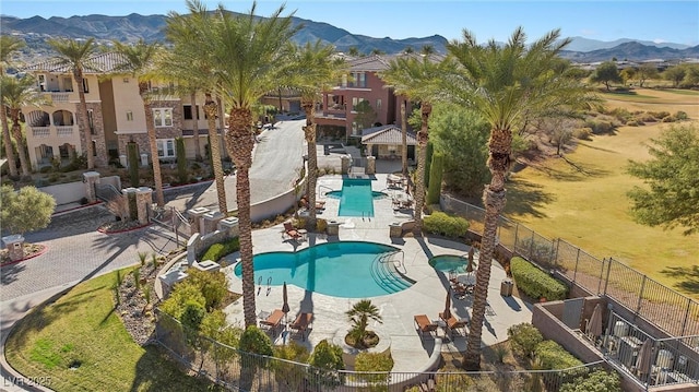 pool with a patio, a mountain view, and fence