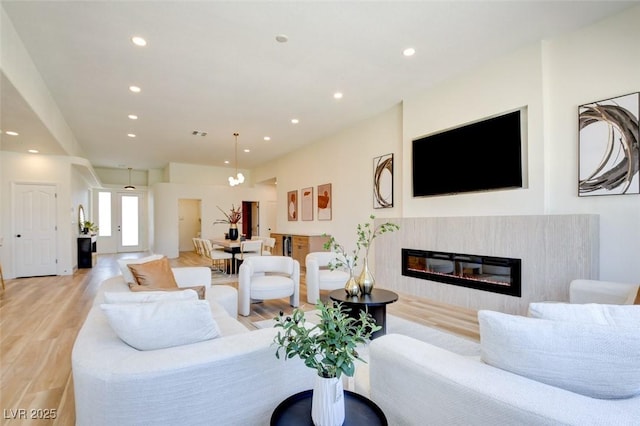 living area featuring a glass covered fireplace, recessed lighting, and light wood-type flooring