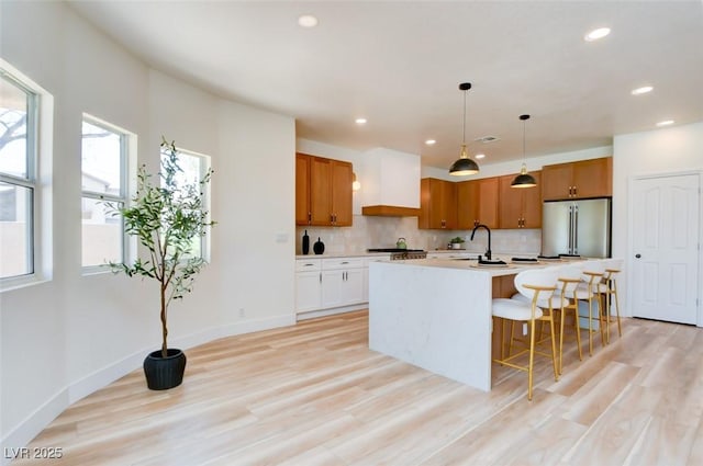 kitchen featuring recessed lighting, a sink, stainless steel fridge, backsplash, and light countertops