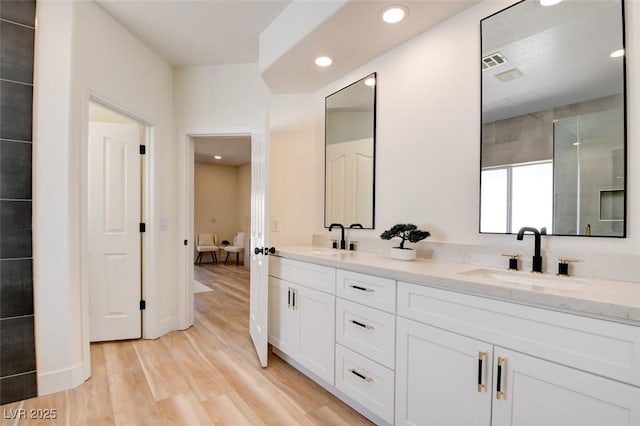 bathroom with double vanity, a sink, wood finished floors, and visible vents