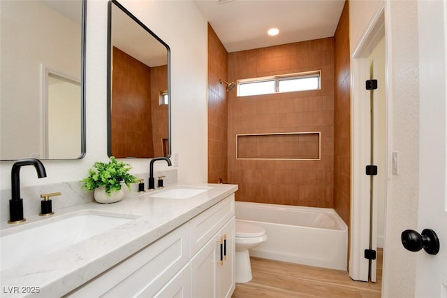bathroom with shower / tub combination, wood finished floors, toilet, and a sink