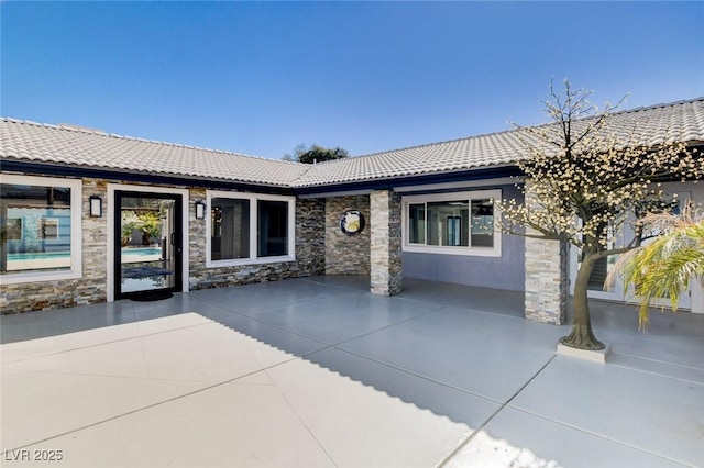 7575 Coley Ave, Las Vegas, NV 89117 - view of front of home with a tile roof, stone siding, and a patio area