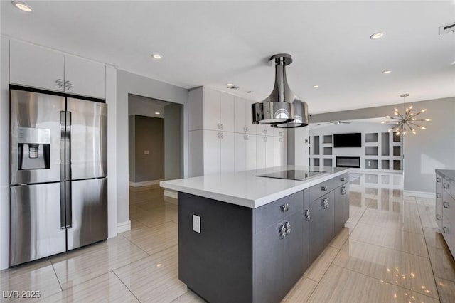 7575 Coley Ave, Las Vegas, NV 89117 - kitchen with stainless steel fridge with ice dispenser, black electric cooktop, a glass covered fireplace, light tile patterned floors, and a chandelier