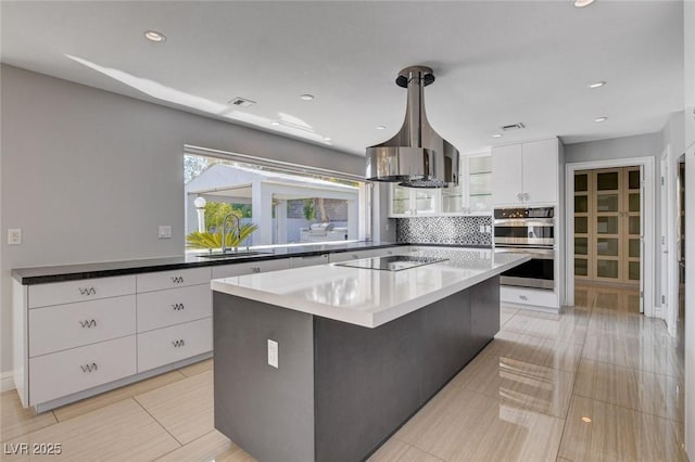 7575 Coley Ave, Las Vegas, NV 89117 - kitchen with stainless steel double oven, black electric stovetop, white cabinetry, a kitchen island, and glass insert cabinets