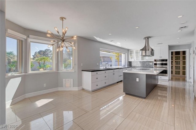 7575 Coley Ave, Las Vegas, NV 89117 - kitchen featuring double oven, a chandelier, white cabinetry, decorative backsplash, and a kitchen island