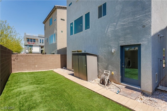 8125 Monsoon Bay St, Las Vegas, NV 89113 - rear view of house with an outdoor structure, a storage unit, a lawn, stucco siding, and a fenced backyard