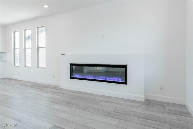 8125 Monsoon Bay St, Las Vegas, NV 89113 - unfurnished living room featuring baseboards, recessed lighting, light wood finished floors, and a glass covered fireplace