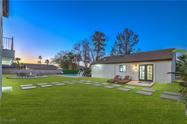 yard at dusk with a patio, a fenced in pool, and french doors