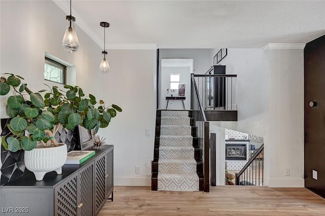 staircase featuring wood finished floors, ornamental molding, and baseboards