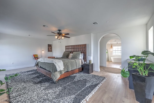 bedroom featuring baseboards, visible vents, arched walkways, and light wood-type flooring