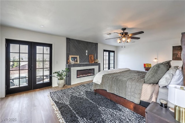 bedroom with a ceiling fan, access to exterior, visible vents, french doors, and wood finished floors