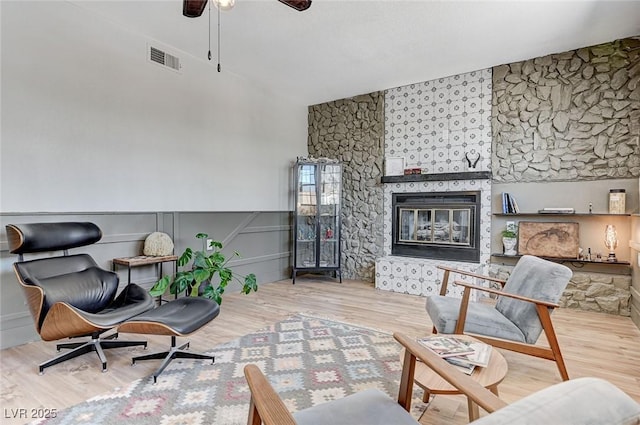interior space with visible vents, wood finished floors, a ceiling fan, and a fireplace