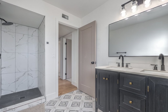 full bath with visible vents, a tile shower, and a sink